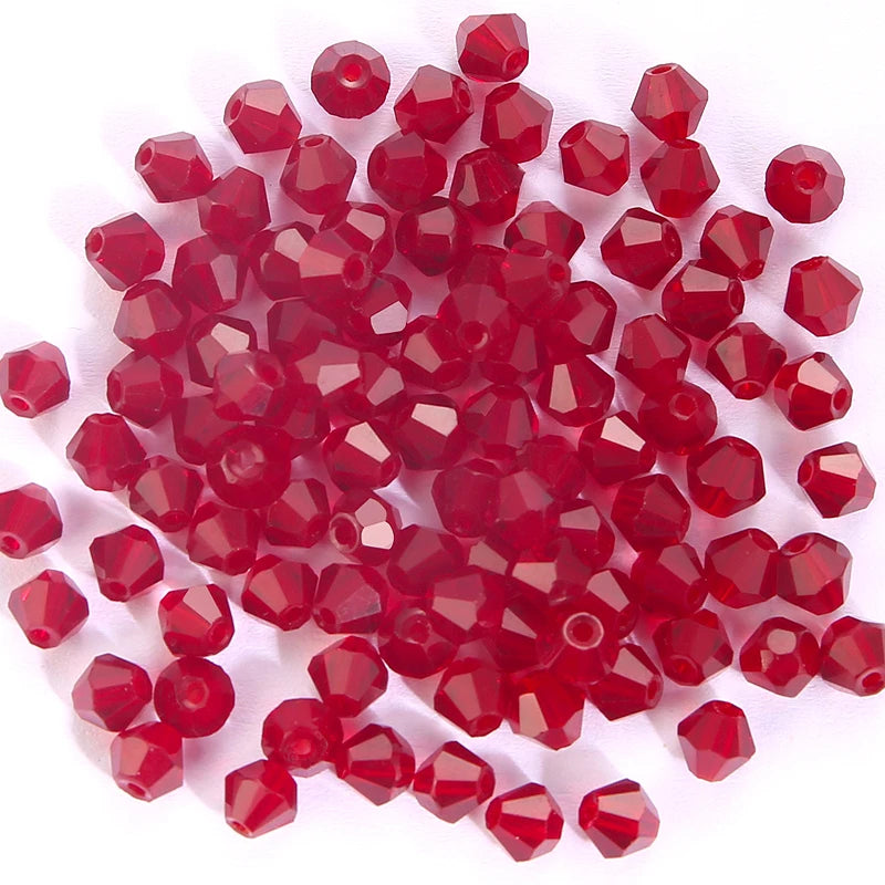 A pile of faceted red crystal bicone glass beads for jewelry making.