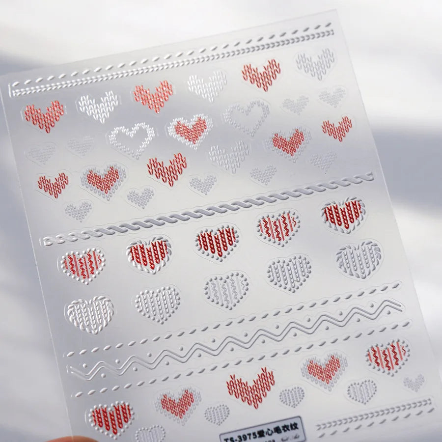 Sheet of white nail art stickers featuring red and gray heart patterns and decorative lines