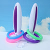 A set of purple and white plastic Easter egg and spoon race game pieces with colored rings on a white surface.