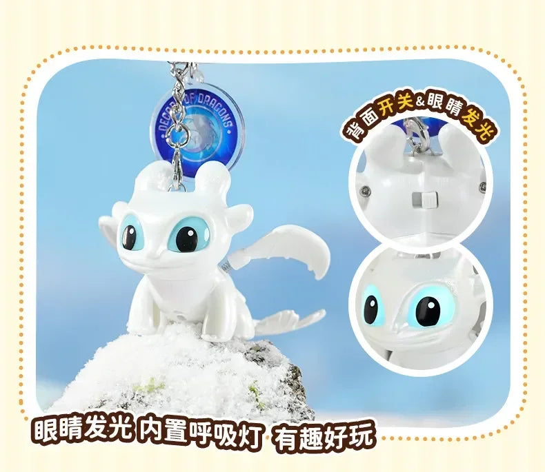 A white Toothless Dragon keychain figurine with movable wings and glowing eyes displayed on a snowy base.