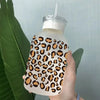 A hand holds a clear plastic cup wrapped with an orange and black leopard print design.