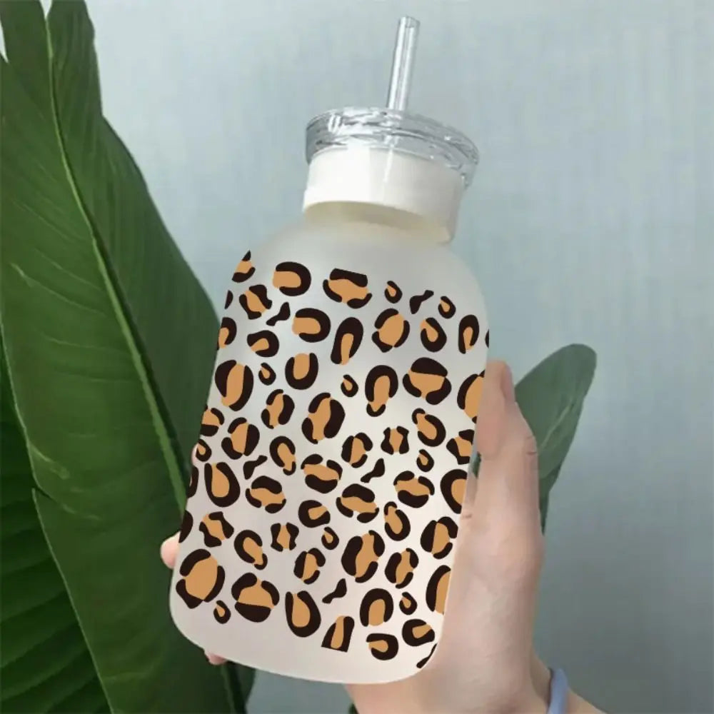 A hand holds a clear plastic cup wrapped with an orange and black leopard print design.