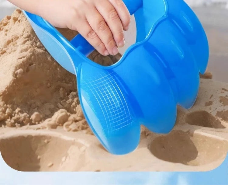 A hand is using a blue dinosaur claw sand digging toy to dig in sand.