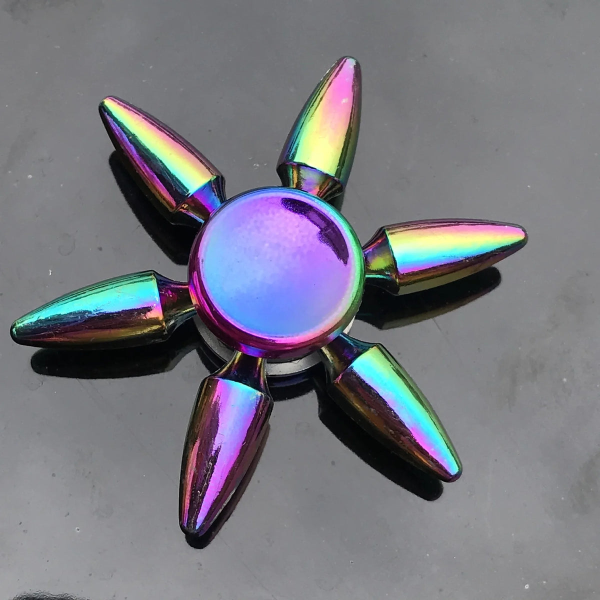 A rainbow metal fidget spinner with smooth silent rotation, featuring iridescent, pointed blades.