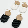 A set of gold-plated earrings featuring roller designs with white and black striped textures.