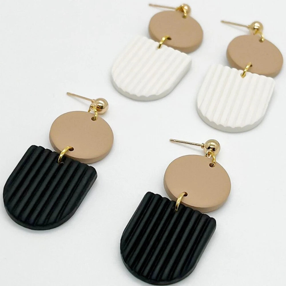 A set of gold-plated earrings featuring roller designs with white and black striped textures.