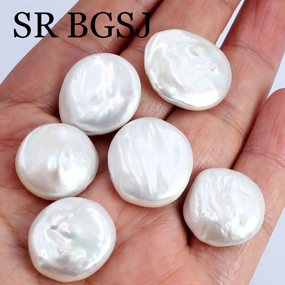 Several natural white freshwater pearl beads are displayed on a hand for jewelry making.