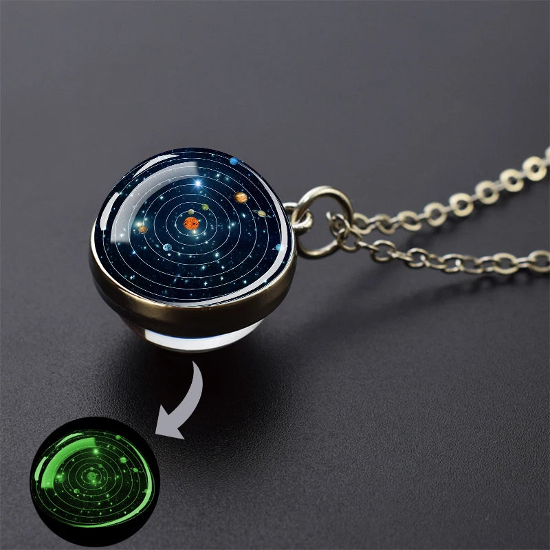 A glow-in-the-dark solar system pendant necklace with a dark blue sphere and a green glowing effect.