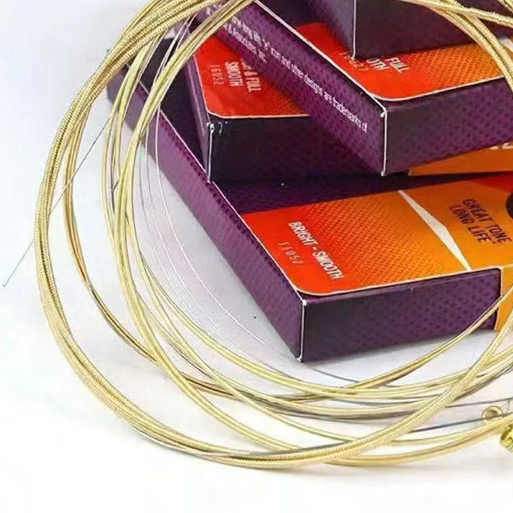 A spool of gold coated acoustic guitar strings with anti-rust protection packaged in purple and orange boxes.