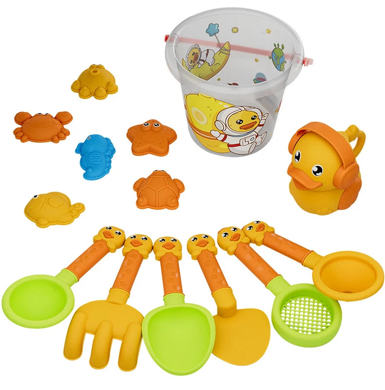 A kids beach sand play set featuring a clear bucket and various orange and yellow plastic toys including a shovel and a mold.