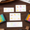 A set of six large rectangular rainbow gradient ink pads for stamping and crafts displayed on a wooden surface.
