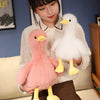 A woman holds two realistic call duck plush toys, one pink and one white, against a blue background.