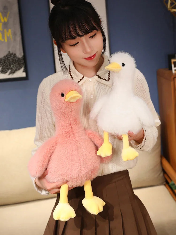A woman holds two realistic call duck plush toys, one pink and one white, against a blue background.