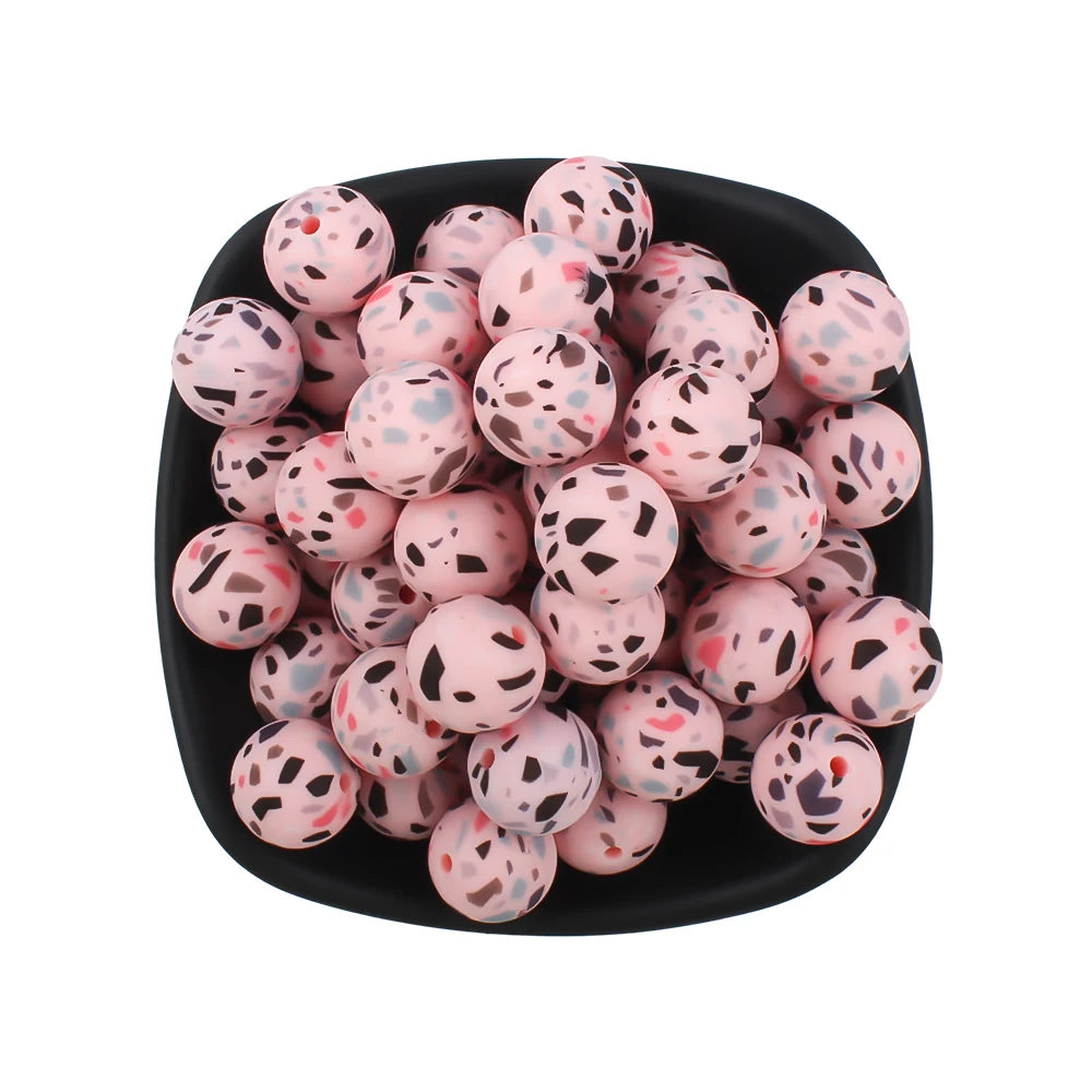 A black bowl filled with pink and leopard-patterned silicone beads for jewelry making.
