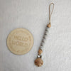 A wooden bead pacifier clip with silicone teether strung on a leather cord.