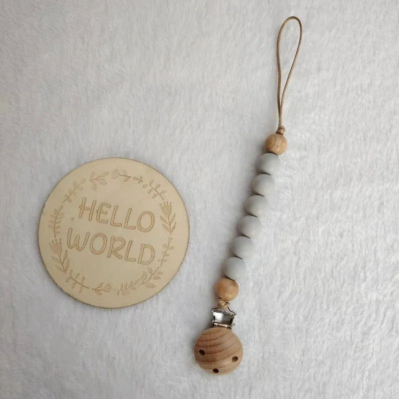 A wooden bead pacifier clip with silicone teether strung on a leather cord.