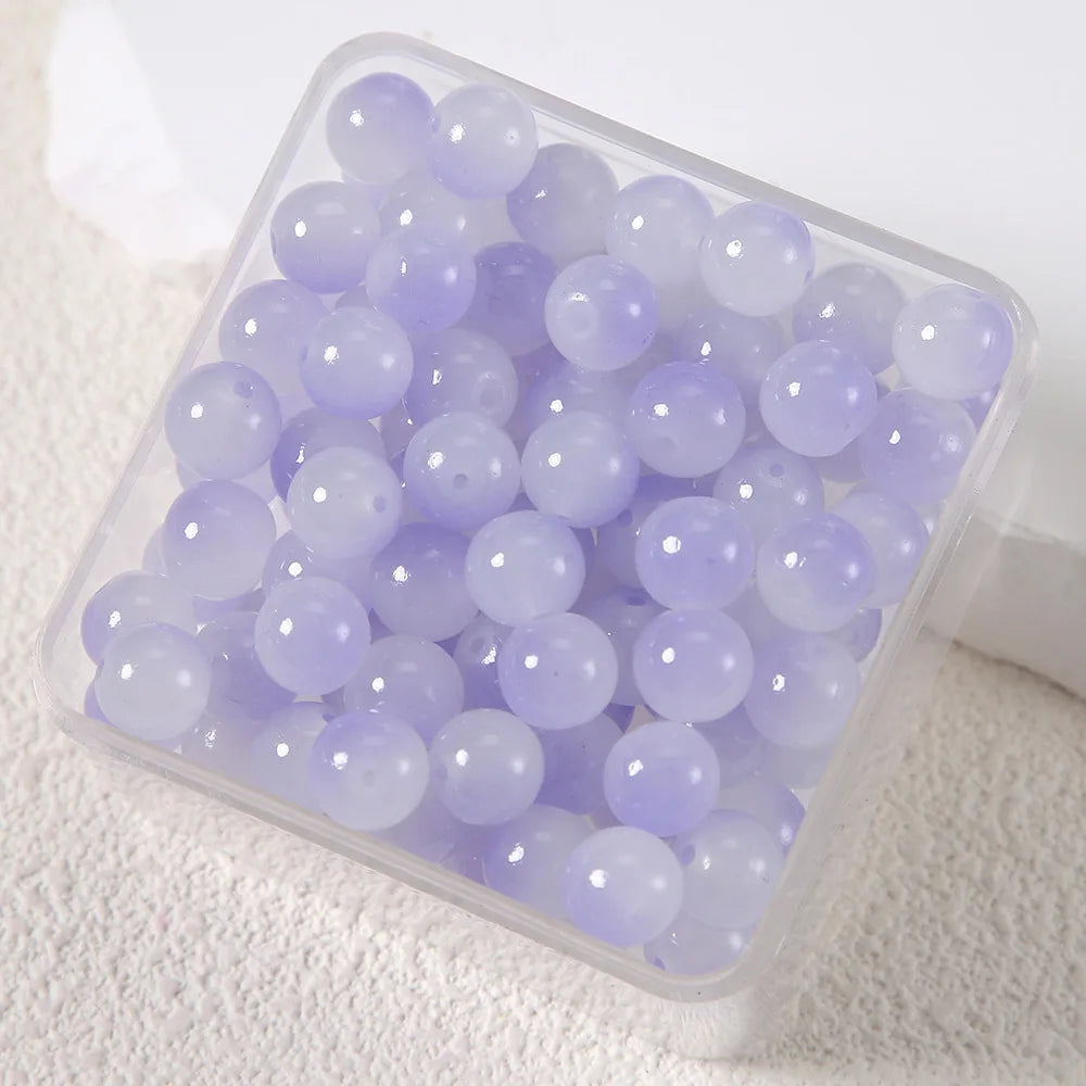 A clear container filled with small, round, purple imitation jade glass beads for jewelry making.
