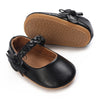Black lace-trimmed moccasin shoes for a baby girl with a bow and tan sole