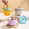 A hand is holding a yellow insulated stainless steel breakfast cup with a green lid, next to other colored cups.