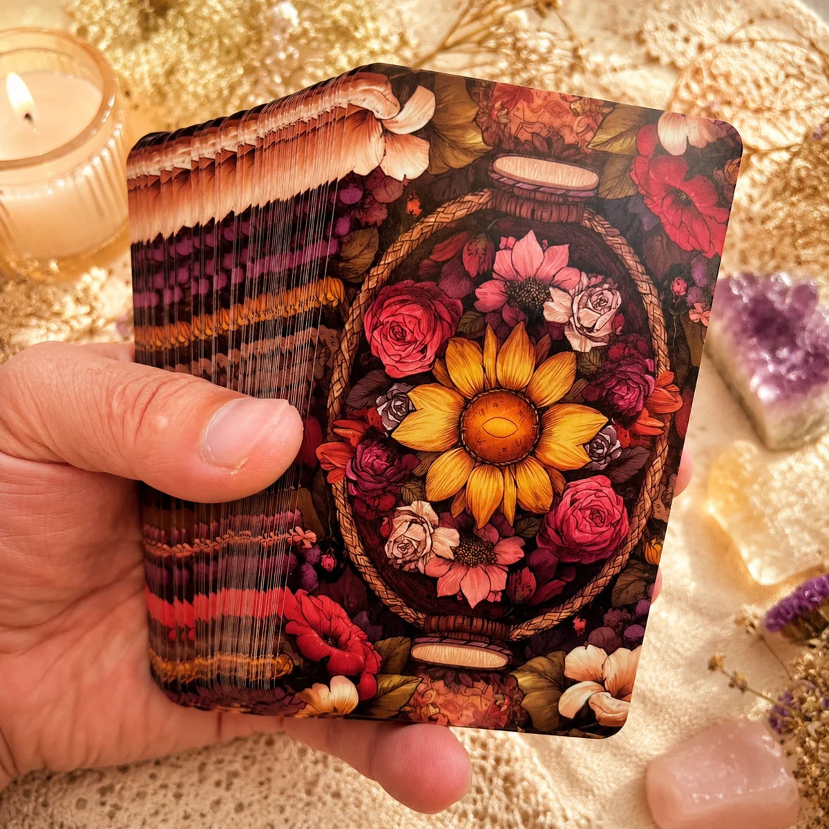 A hand holds a tarot deck featuring floral and earthy tones, set against a gold textured background.