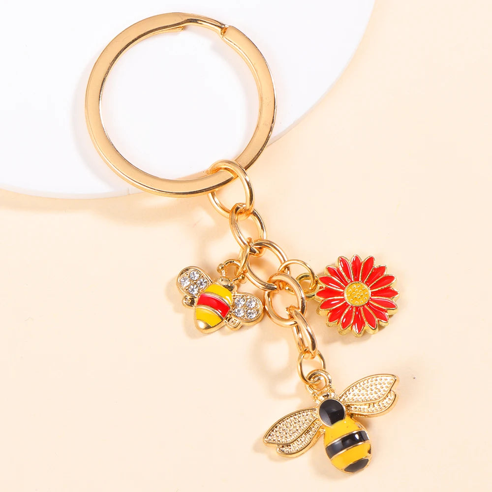 Gold-toned enamel flower keychain featuring a bee and a daisy design.