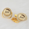 A gold-toned crystal pacifier and clip set featuring a circular charm engraved with the name Jose