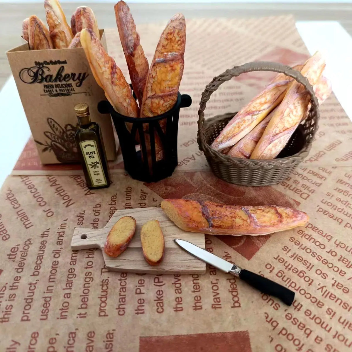 A miniature baguette is displayed alongside a basket of breadsticks and packaged in a brown paper bag.