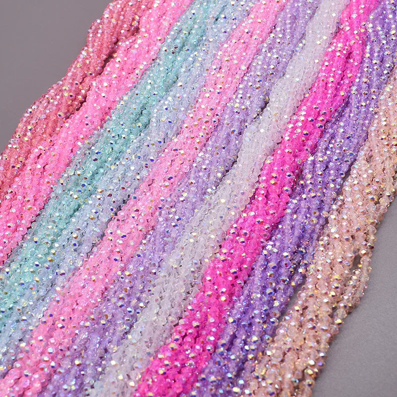 A close-up of multicolored faceted crystal rondelle beads in various shades of pink, purple, and teal.