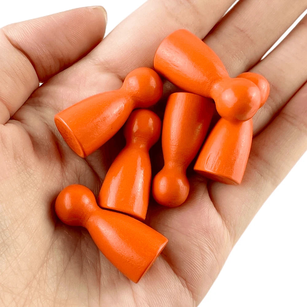A hand holds a set of twelve wooden game pawns in six different shades of orange.