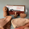 A box of ROCK CLAY modeling clay is shown next to a hand-formed piece of the clay.