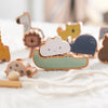 A collection of wooden animal figures, including a green crocodile and various other animals, laid out on a white cloth.