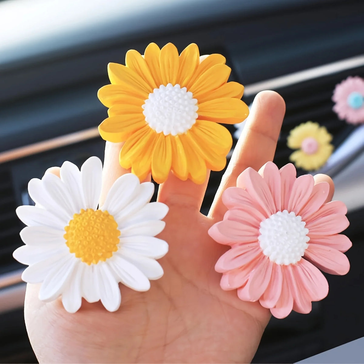Une main tient quatre moules de fleurs marguerites en silicone dans les couleurs blanc, orange, jaune et rose pour la créatio