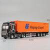 Diecast model of an orange Hapag-Lloyd container truck with black cab and multiple axles.