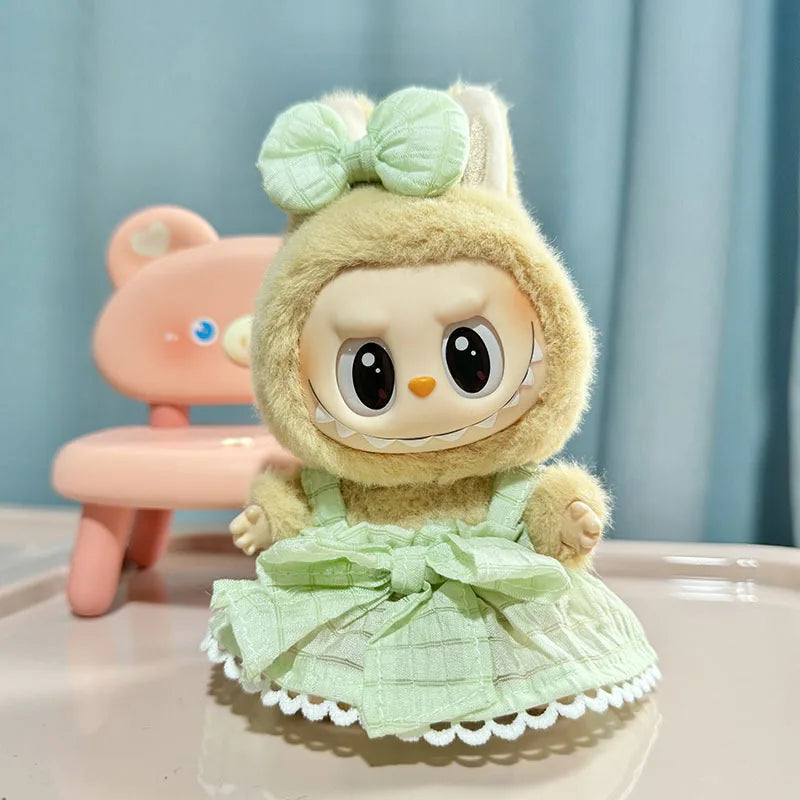 A cute plush doll wearing a light green dress and bow, sitting in front of a pink chair.