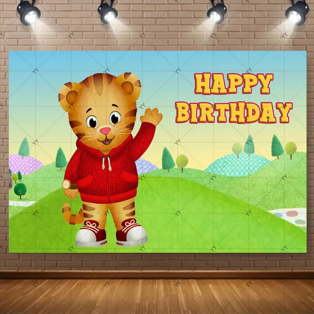 A cute cartoon tiger character with a red hoodie celebrating a happy birthday against a green outdoor background.