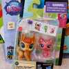 A clear plastic package containing three small animal figures, including a yellow fox, a pink cat, and a white figure.