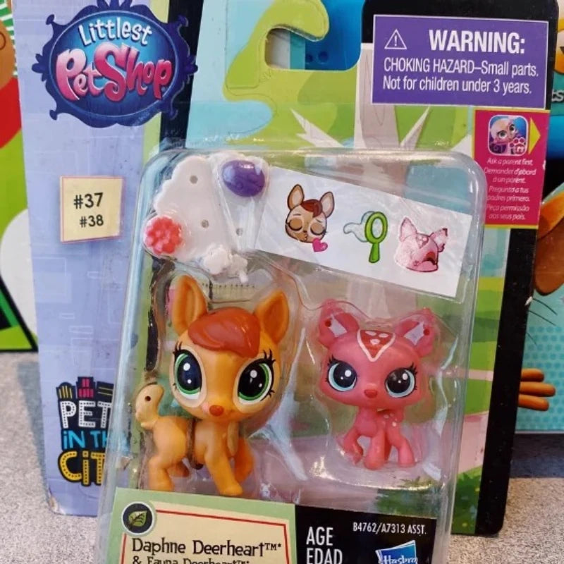 A clear plastic package containing three small animal figures, including a yellow fox, a pink cat, and a white figure.