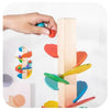 A hand is placing a colored wooden block onto a vertical wooden track toy for learning.