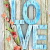 Wooden letters spelling LOVE made of distressed blue wood with pink floral vines