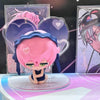 A pink-haired figure with blue accents is displayed in a blind box packaging featuring heart shapes.
