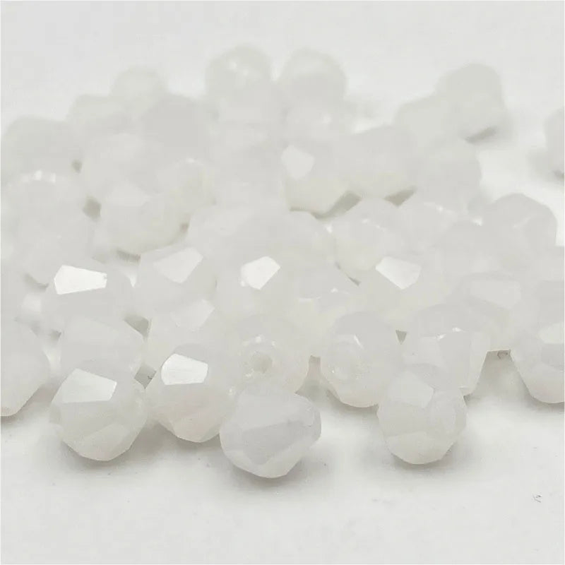 A pile of clear white faceted bicone crystal glass beads for jewelry making.