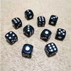 A collection of ten black and white six-sided dice scattered on a light wooden surface.