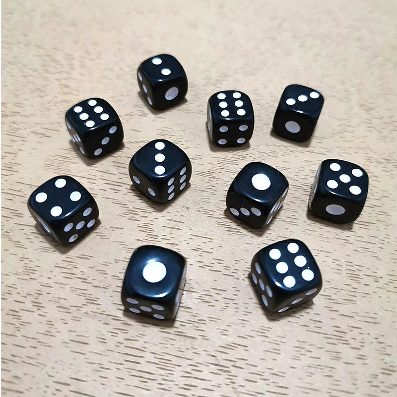 A collection of ten black and white six-sided dice scattered on a light wooden surface.
