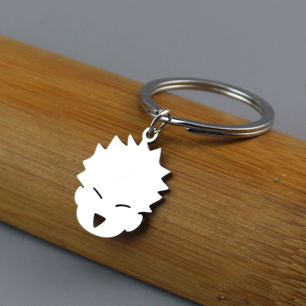 A white silhouette of a spiky-haired anime character charm attached to a silver keychain ring, resting on a wooden surface.