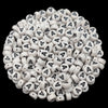 A close-up view of numerous white acrylic alphabet letter beads scattered on a dark background.