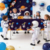 Children dressed as outer space astronauts posing with balloons and space-themed decor