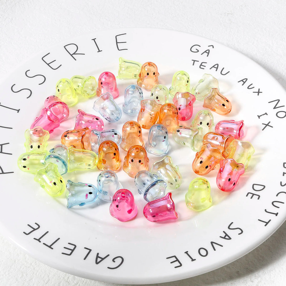 A collection of colorful acrylic ghost beads arranged on a white plate.