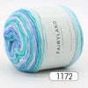 Spool of Fairyland long distance cake ball yarn in gradient blue and white colors.