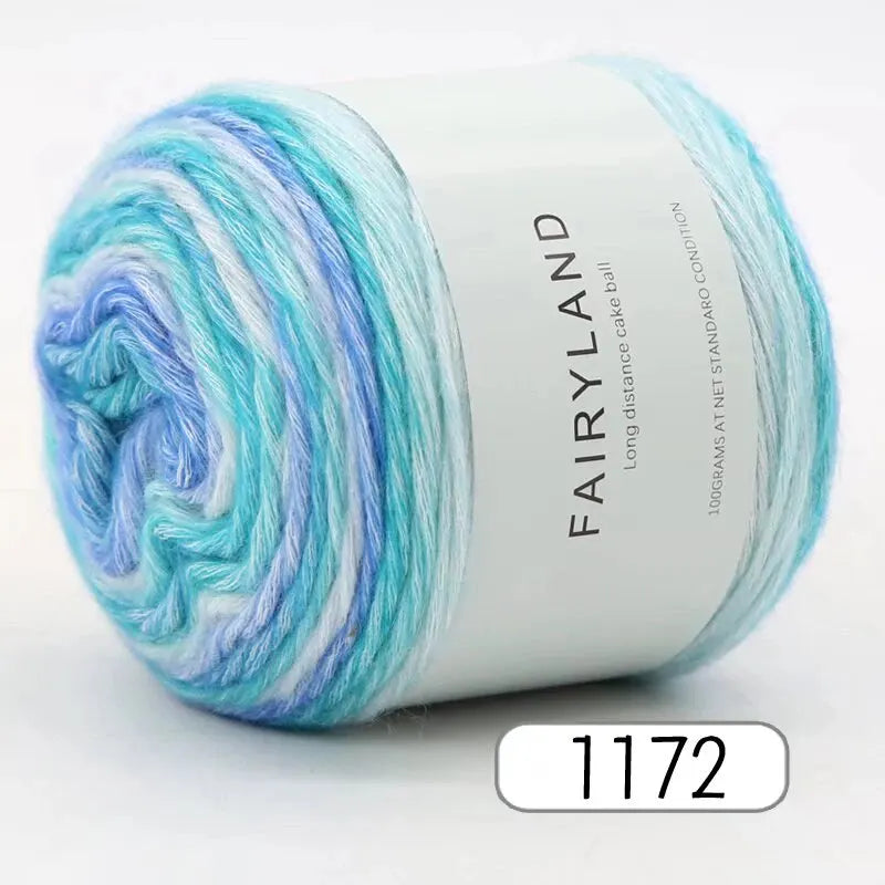 Spool of Fairyland long distance cake ball yarn in gradient blue and white colors.