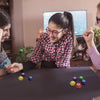 A girl is playing the Traditional Korean Gonggi Stone Game with several colored pebbles on a dark table.